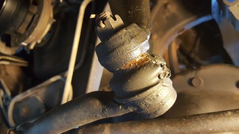 1996 Ford Bronco - Close-up of a damaged ball joint, indicating wear and tear on the steering component.