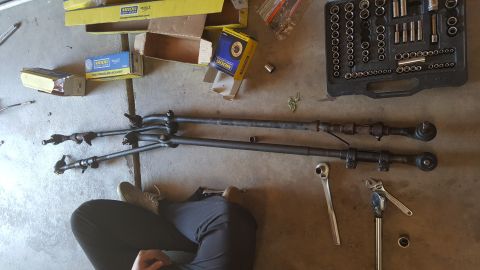 1996 Ford Bronco - Steering linkage parts and tools are laid out on the floor, possibly for a repair or replacement.