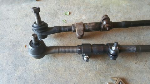1996 Ford Bronco - Close-up view of two automotive steering tie rods laid out on a textured surface.