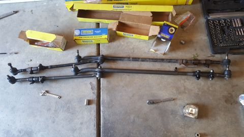 1996 Ford Bronco - Several MOOG steering linkage components and various tools are laid out on a concrete surface.