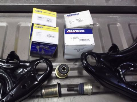 2001 Mercury Grand Marquis - Various front end suspension components, including control arms and bushings, are laid out with their respective ACDelco and Moog packaging.