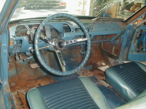 1967 Ford Mustang - The interior of a 1967 Ford Mustang shows significant rust and damage, including a cracked windshield and missing dashboard components.