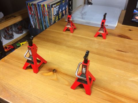 1989 Ford Bronco - Four red 6-ton jack stands are arranged on a wooden surface, with magazines in the background.