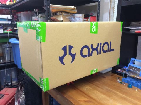 1989 Ford Bronco - A cardboard box with the Axial logo is taped and sits on a table, with shelves and other items in the background.