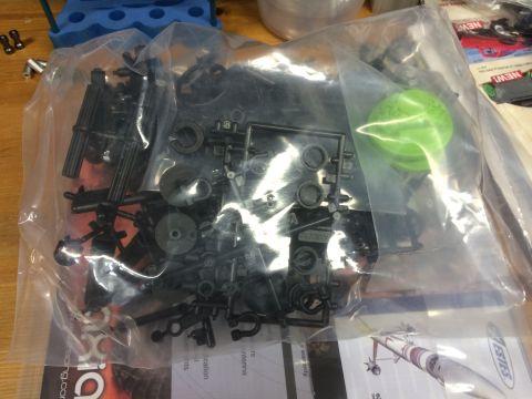 1989 Ford Bronco - A collection of unassembled model car parts are contained within a clear plastic bag on a wooden surface.