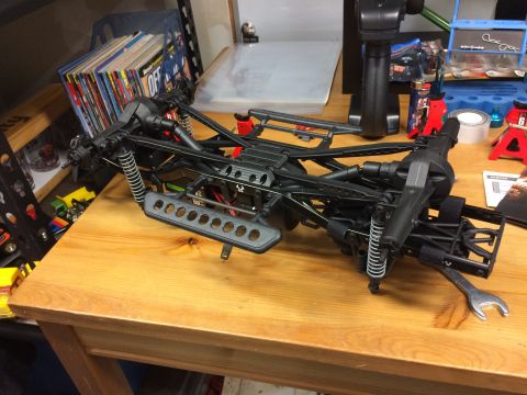 1989 Ford Bronco - The chassis of a remote-controlled car, its suspension and drivetrain, rests on a wooden surface.