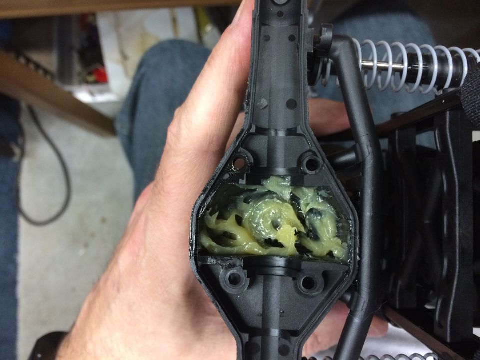 RC car differential housing filled with yellow grease and gears