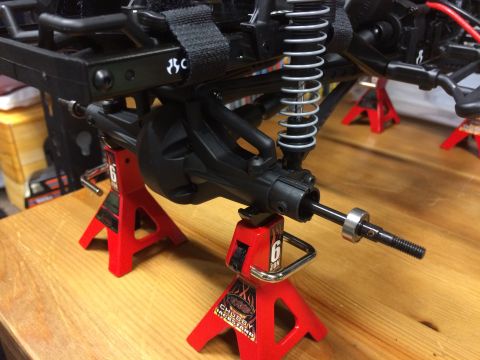 1989 Ford Bronco - Close-up of an RC car's suspension and drivetrain components supported by red jack stands.
