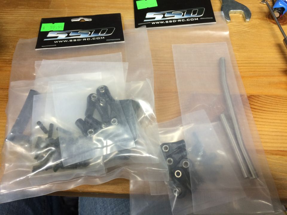 Two bags of RC car parts on a wooden table. One bag has an SSD RC header card.