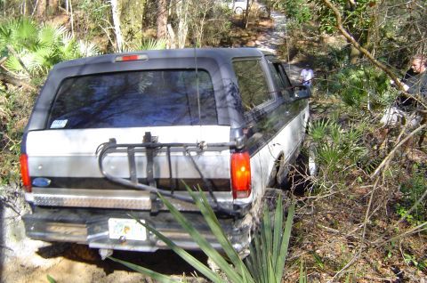 1993 Ford Bronco - A 1993 Ford Bronco navigates a wooded trail, with another vehicle visible in the distance.