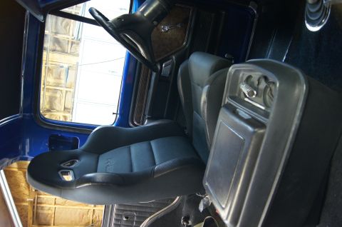 1979 Ford Bronco - Interior view of a blue Ford Bronco showing racing seats, a center console with cup holders, and the steering wheel. The driver's side door…