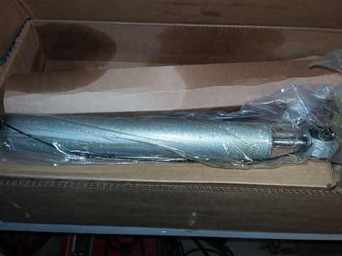 1996 Ford Bronco - A silver shock absorber is shown inside a cardboard box, wrapped in clear plastic packaging.