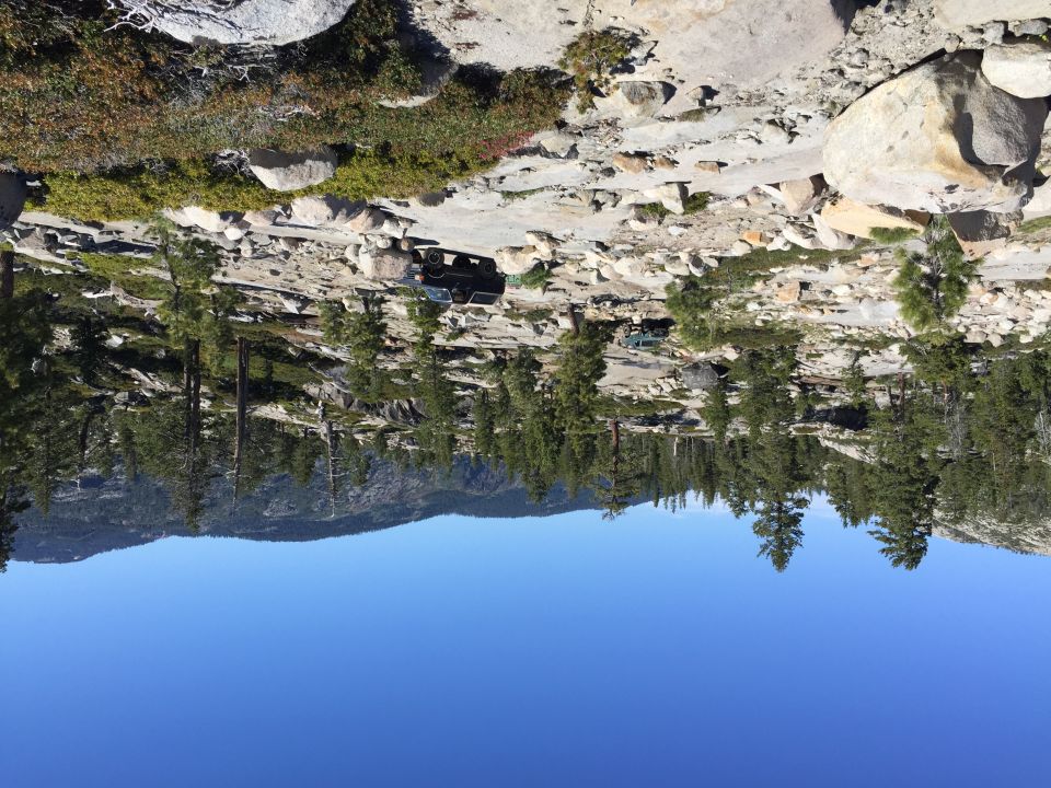 Photo of off-road vehicles on granite among pines under blue sky