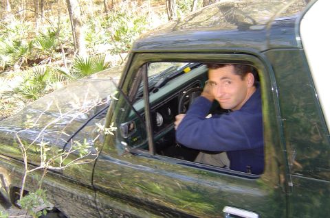 1993 Ford Bronco - Driver in a green 1970s Ford F-Series truck, seen from the side with the door open.
