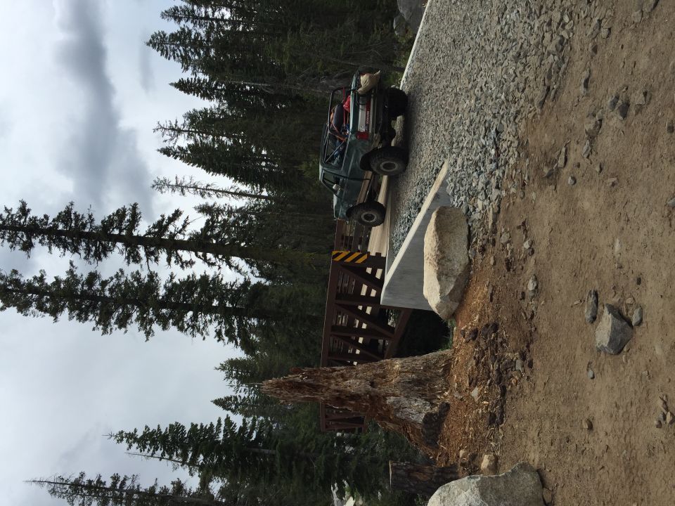 Lifted pickup crossing a small wooden bridge in a forest