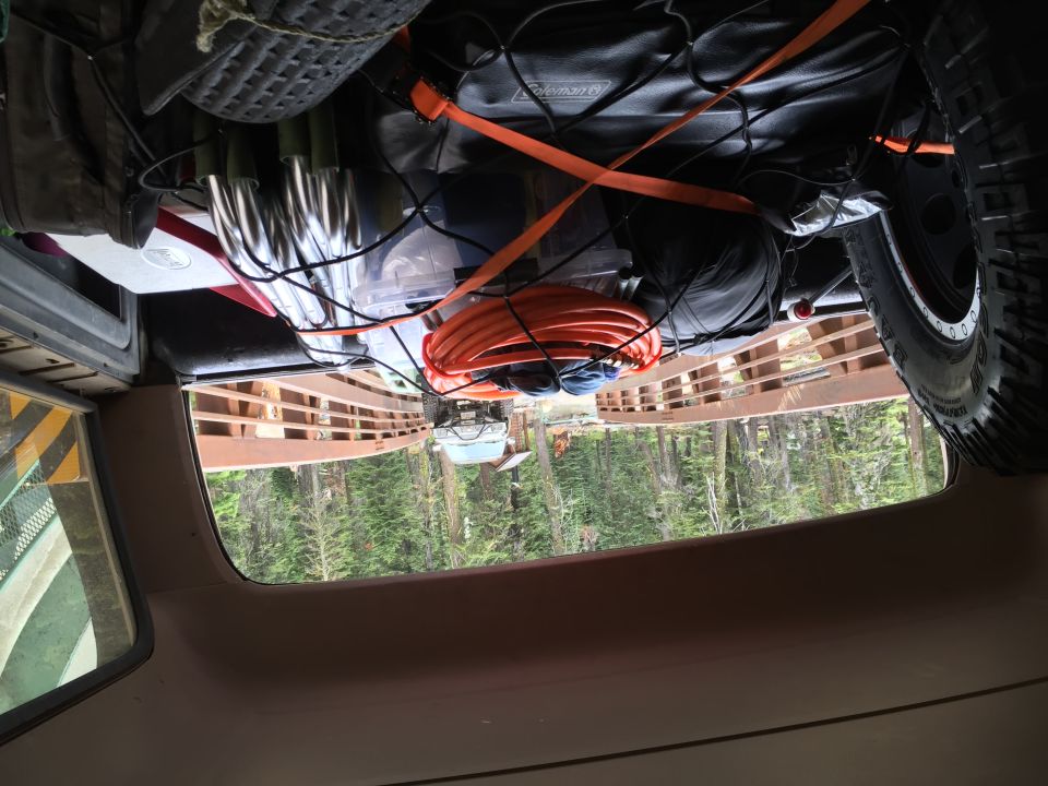 View from inside a truck cargo area loaded with gear and a spare tire