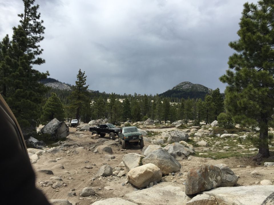 Off-road vehicles on a granite expanse under a stormy sky