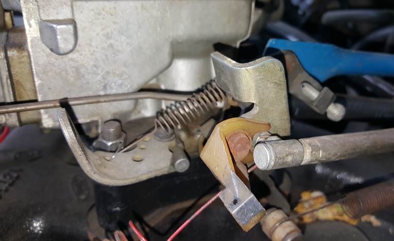 Close-up of carburetor throttle linkage and return spring.