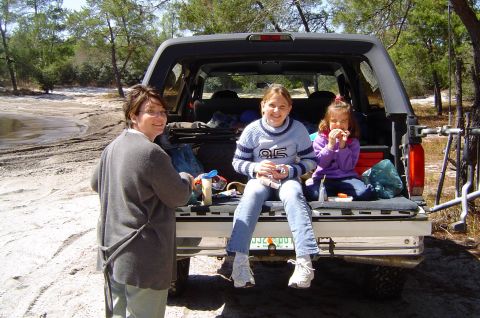 1993 Ford Bronco - A family enjoys a break outdoors, with the open tailgate of their Ford Bronco serving as a makeshift bench.