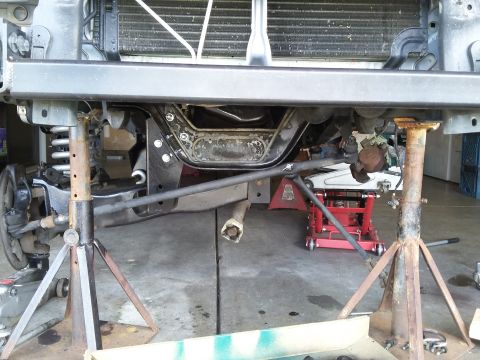 1996 Ford Bronco - The underside of a vehicle, likely a 1996 Ford Bronco, is supported by jack stands and a hydraulic jack. Components of the suspension and s…