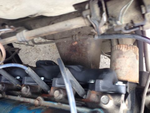 1979 Ford Bronco - A close-up view of the engine bay of a vehicle, focusing on the spark plug wires and exhaust manifold.