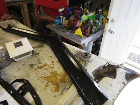 Black car trim piece on a workbench with tools and bottles in background