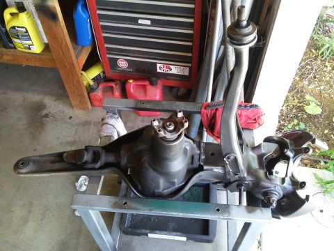 1996 Ford Bronco - A disassembled rear differential and suspension assembly, likely from a 1996 Ford Bronco, is shown resting on a metal stand in a garage set…