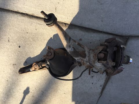 1996 Ford F-150 - A disassembled front suspension component lies on a concrete surface, showing signs of rust and wear.