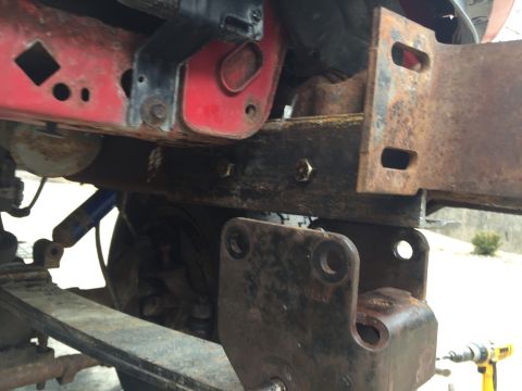 1996 Ford F-150 - Close-up view of heavily rusted truck frame and suspension components, showing leaf springs and shock absorber.