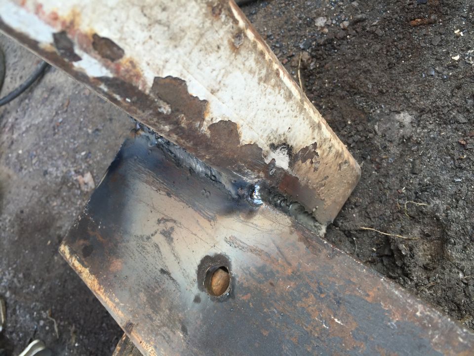 Close-up of two rusty metal pieces joined by a weld, with a bolt visible on one piece