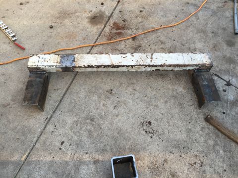 1996 Ford F-150 - A white metal frame with welded steel legs sits on a concrete surface, exhibiting signs of rust and wear.