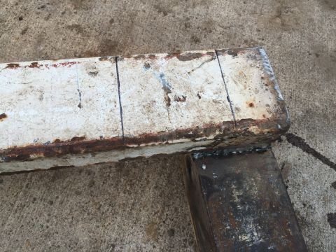 1996 Ford F-150 - A close-up view of a rusty metal beam with visible cut marks and evidence of recent welding.