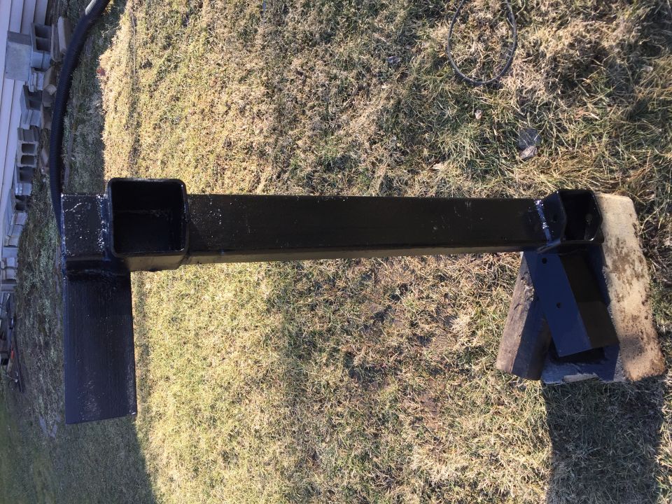 Black trailer hitch receiver mounted on wooden blocks on grass