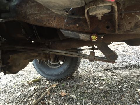 1996 Ford F-150 - The rear leaf springs and axle housing of a heavily rusted pickup truck are visible from below.