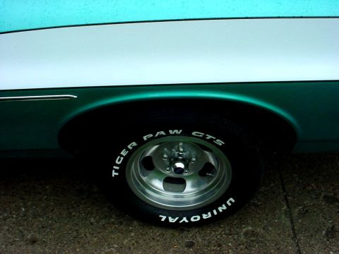 1973 Ford Ranchero - Close-up of a vehicle's side, teal and white paint, chrome wheels, and Uniroyal Tiger Paw tires.