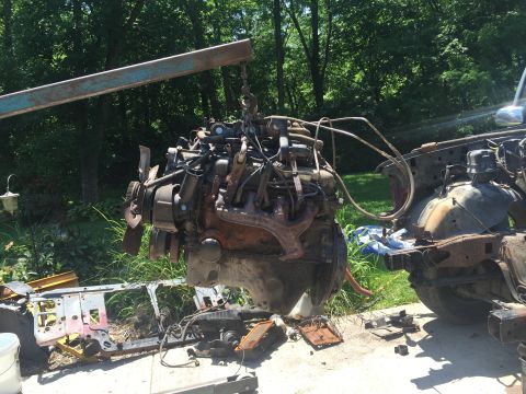 1967 Ford Custom Wagon - An engine is being removed from a vehicle using an engine hoist, with the car's chassis in the background.
