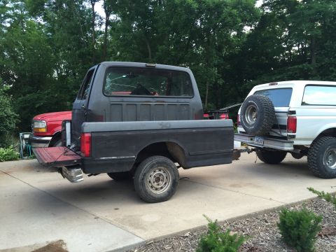 1967 Ford Custom Wagon - A dark pickup truck is hitched to a trailer carrying a white SUV, with another pickup truck behind it.