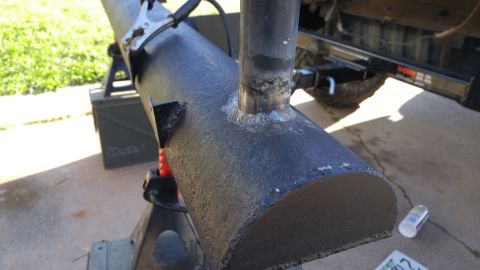 1978 Ford Bronco - A section of pipe, likely a custom exhaust or bumper component, is supported by jack stands and appears to be undergoing welding or modific…