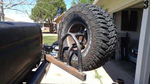 1978 Ford Bronco - A large off-road spare tire is mounted on a custom metal rack attached to the rear of a vehicle.