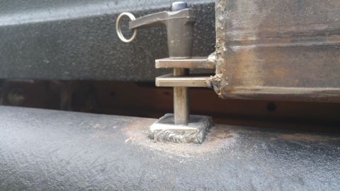 1978 Ford Bronco - Detail of a metal latch mechanism, likely for a tailgate or spare tire carrier, on a vehicle's rear.