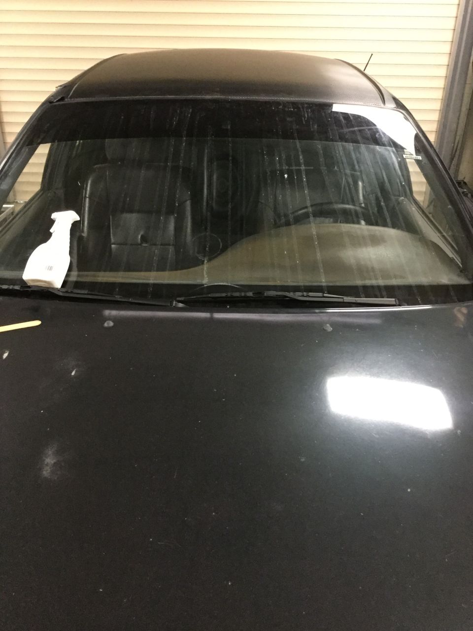 Car hood and windshield interior. Spray bottle on dashboard