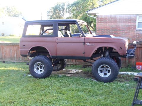 1972 Ford Bronco - A lifted Ford Bronco sits in a grassy yard with a brick house in the background.