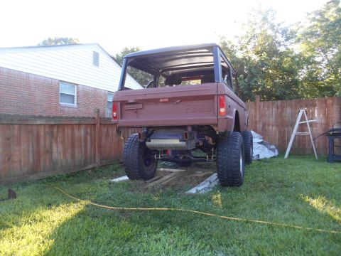 1972 Ford Bronco - This 1972 Ford Bronco is undergoing restoration, as seen from its rear in a grassy yard with a wooden fence.