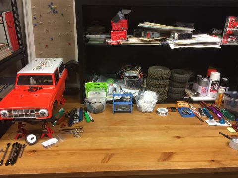 1989 Ford Bronco - RC car body and various hobby supplies are laid out on a workbench for assembly or modification.