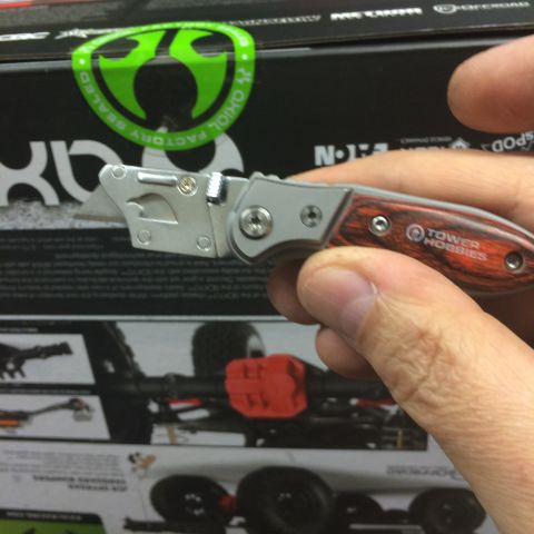 1989 Ford Bronco - A folding utility knife with a wood-grain handle is held in front of a box for an RC car.