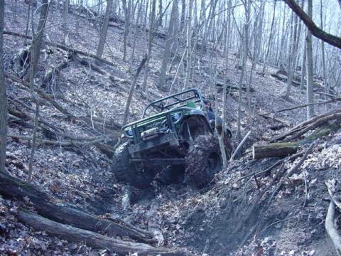 1992 Ford Bronco - An off-road vehicle tackles a challenging, steep trail in a dense forest.