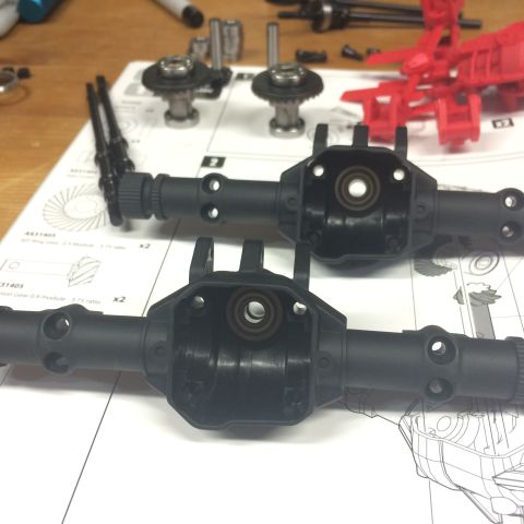 1989 Ford Bronco - RC car axle parts and assembly instructions are spread out on a table.