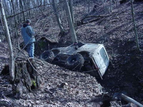 1992 Ford Bronco - A person observes an off-road vehicle that has become stuck in a steep, wooded ravine.