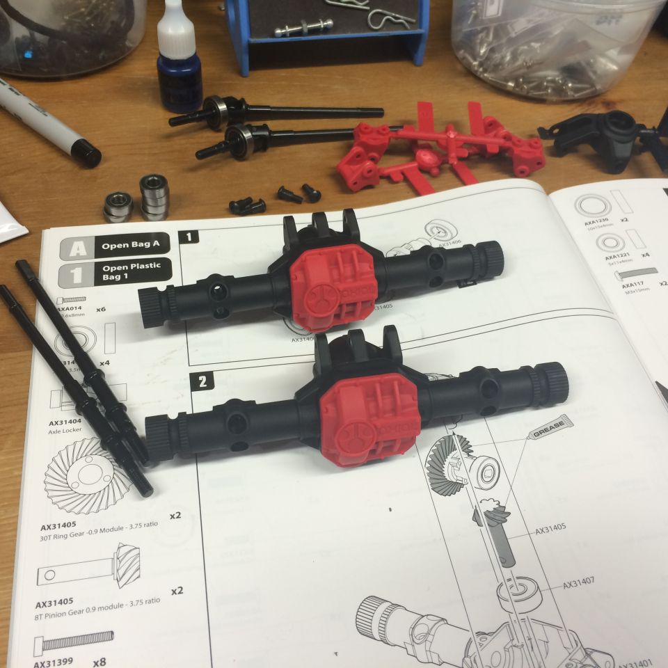 Model vehicle axles and instruction manual on a wooden surface