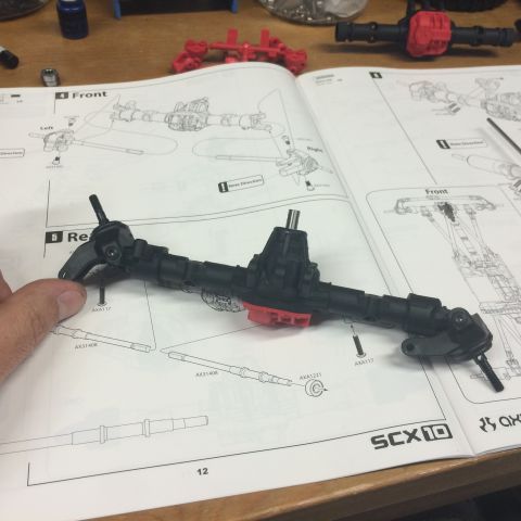 1989 Ford Bronco - An RC car axle assembly is shown on an SCX10 instruction manual, with other parts in the background.